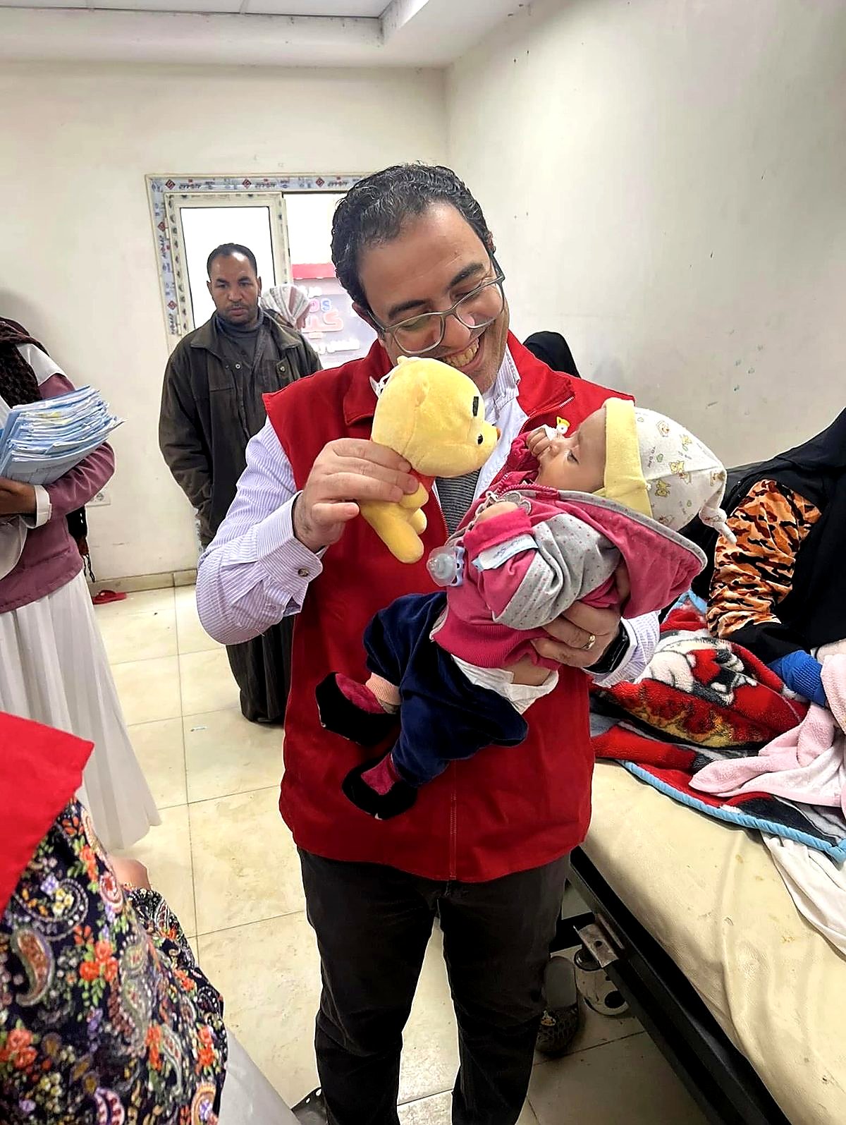 A volunteer presenting a teddy to an infant